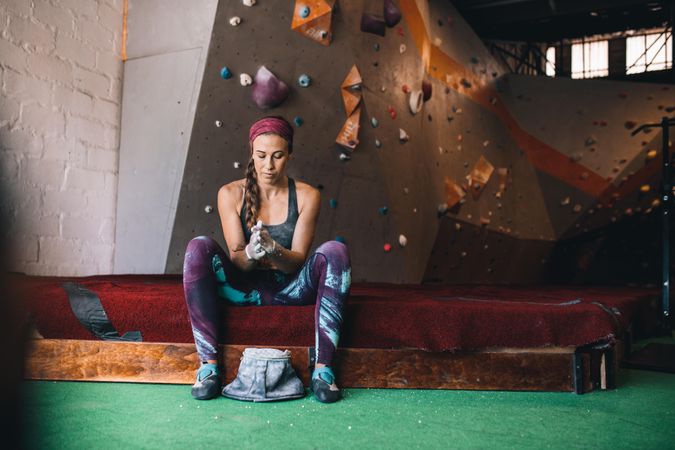 Female rock climbing instructor using powder to prep hands for climbing