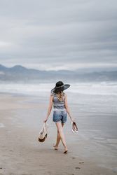 Young female walking barefoot on sandy beach