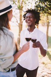 A man and woman talking outside holding wine