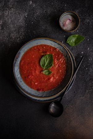 Top view traditional Spanish gazpacho with basil leaf garnish