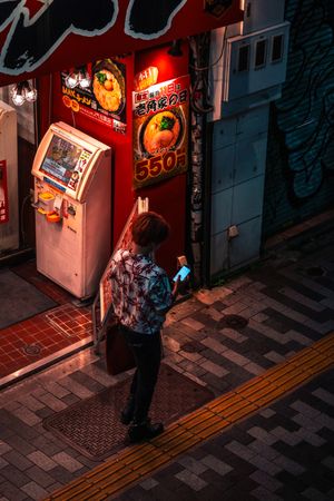 Top view of a person standing on sidewalk using smartphone at night