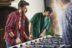 Group of cheerful young people friends playing table football together 4MGxKr
