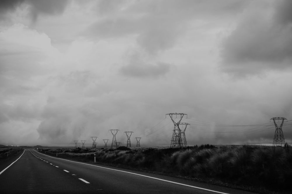 Empty road and electric poles under stormy sky