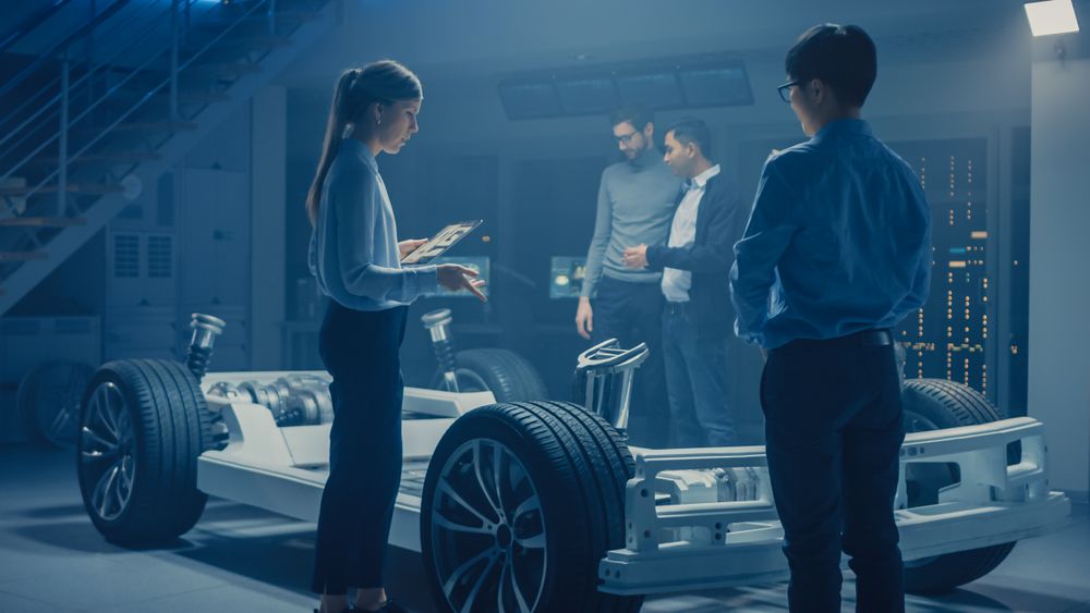 Automobile Engineers Discussing and Designing Electric Car Chassis Platform, Using Tablet Computers with 3D CAD Software.
