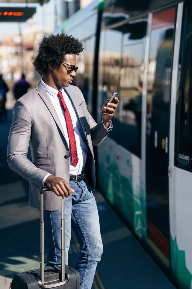 Man in jeans and dress shirt with tie standing next to train