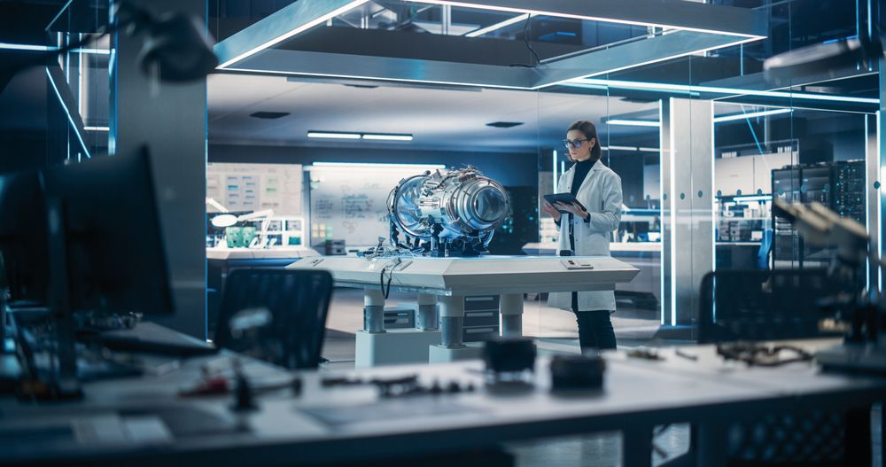 Young Industrial Turbine Specialist in Glasses Standing at a Table With an Innovative Invention.