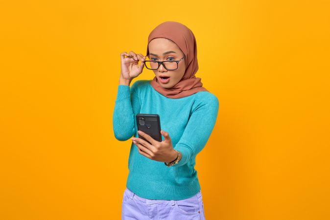 Smiling Muslim woman adjusting her eyeglasses