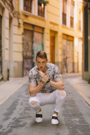 Handsome man sitting on asphalt