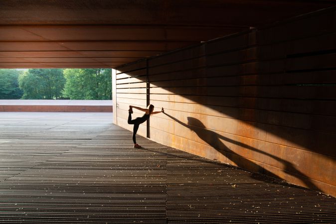 young woman stretching leaning in a amazing geometrical building
