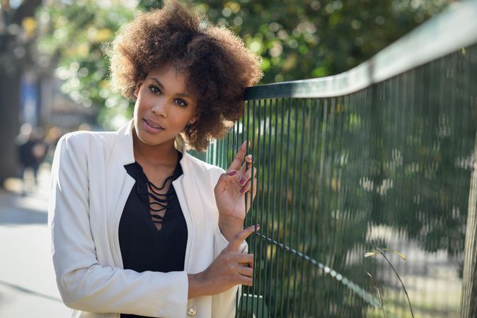 Female with afro looking at camera while standing holding fence