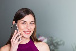 Smiling woman speaking on smartphone at home
