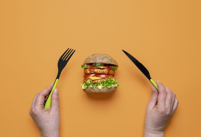 Eating vegan burger top view on an orange background