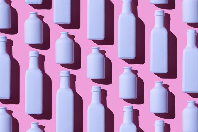 Light purple painted glass bottles laying on pink background