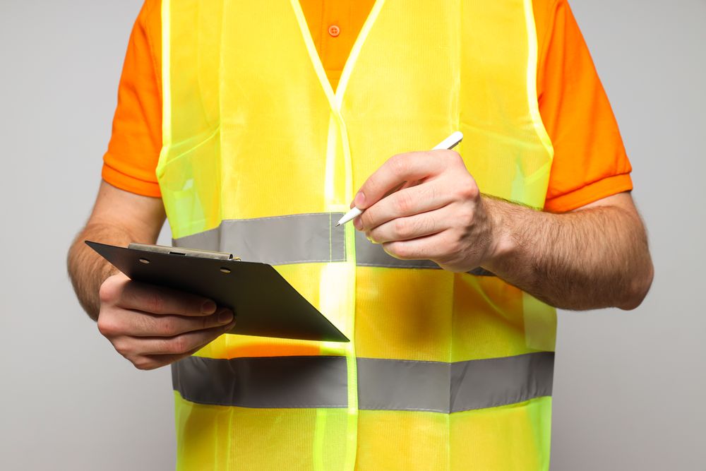 Civil engineer with clipboard on gray background