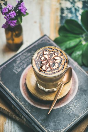 Top view of latte with decorative pattern in chocolate syrup on coffee book