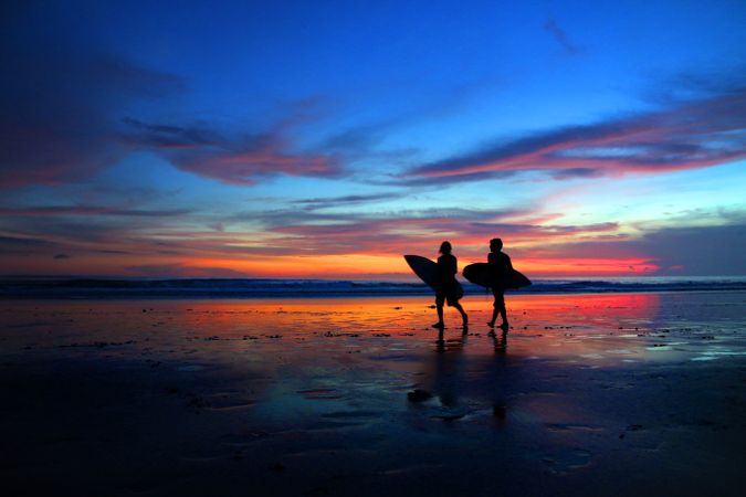 Surfers walking at sunset