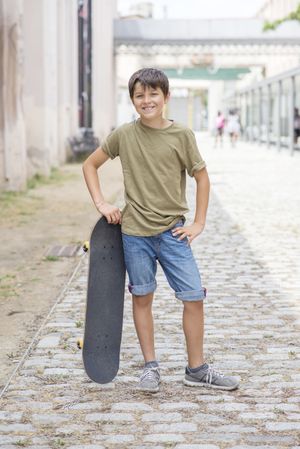 A teenage boy posing with skateboard and smiling