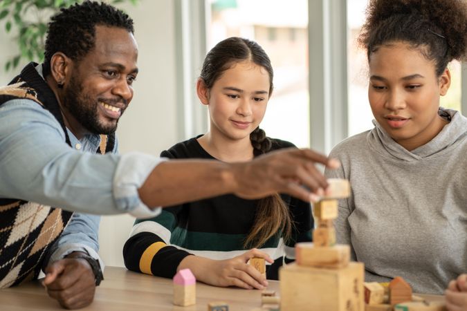 Black male teacher with wood blocks with two female students