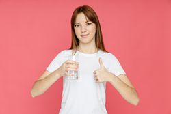 Concept of people, woman with glass of water on pink background