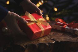 Man holding Christmas gift by wooden table