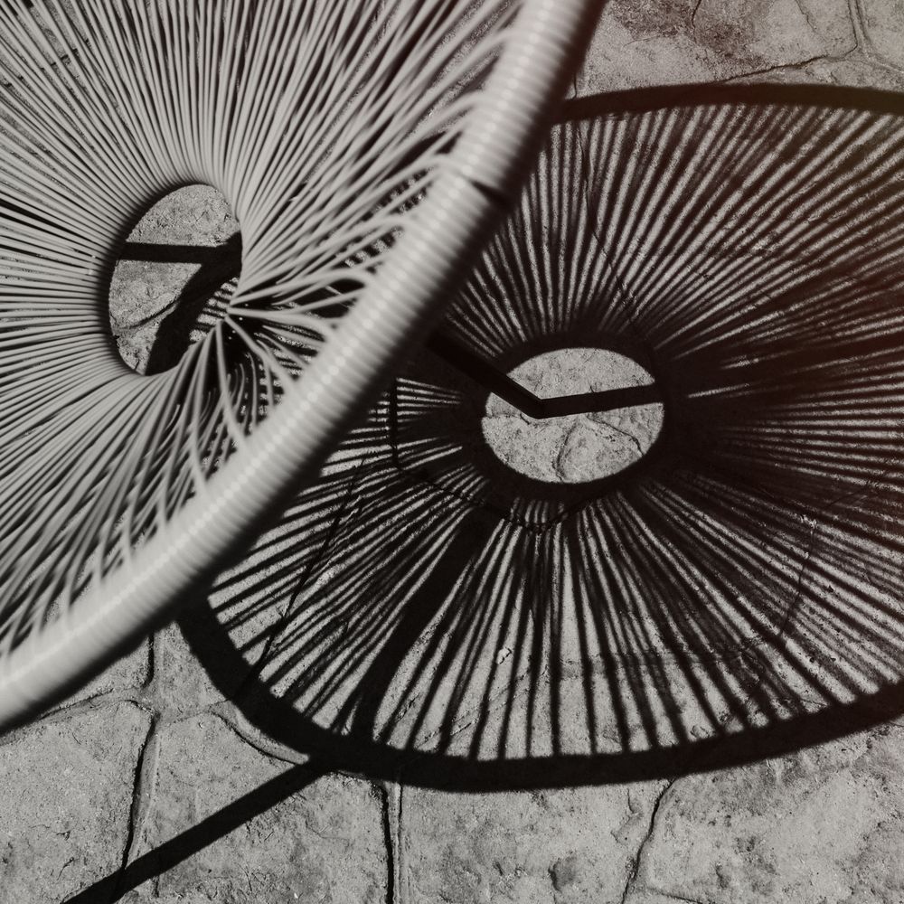 Modern wicker chair leaving shadow on stone pavement