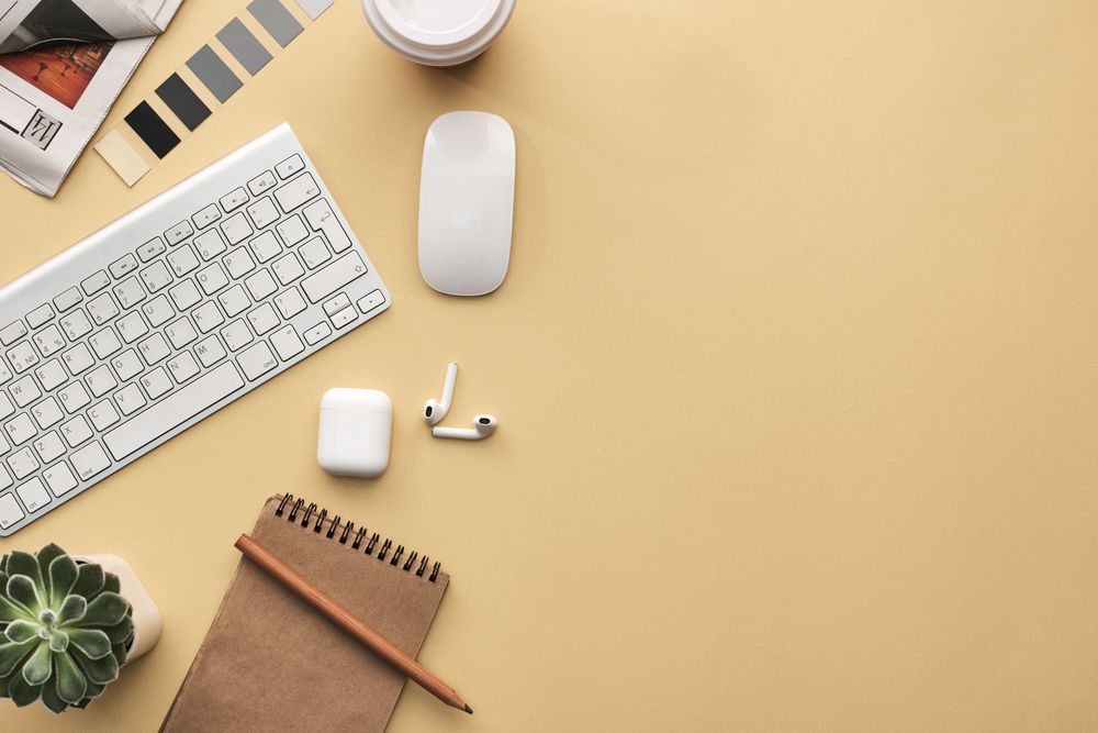 Top view of Apple products and notebook on yellow table