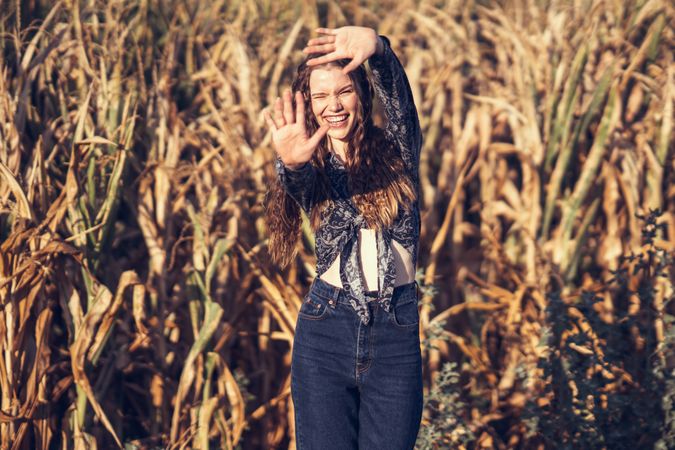 A carefree woman joyfully plays in a sunny cornfield, embracing lifes beauty around her