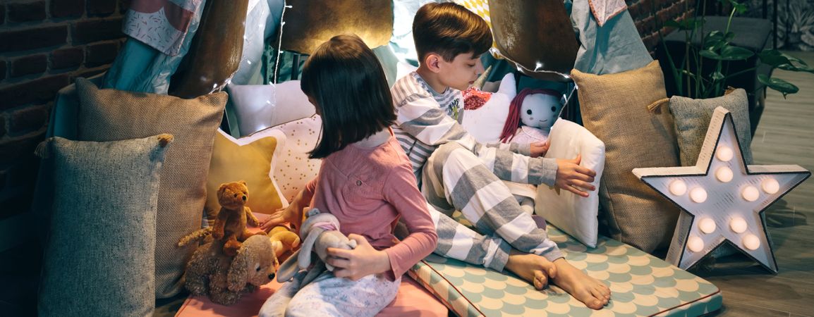 Children preparing tent with chairs and bed sheets