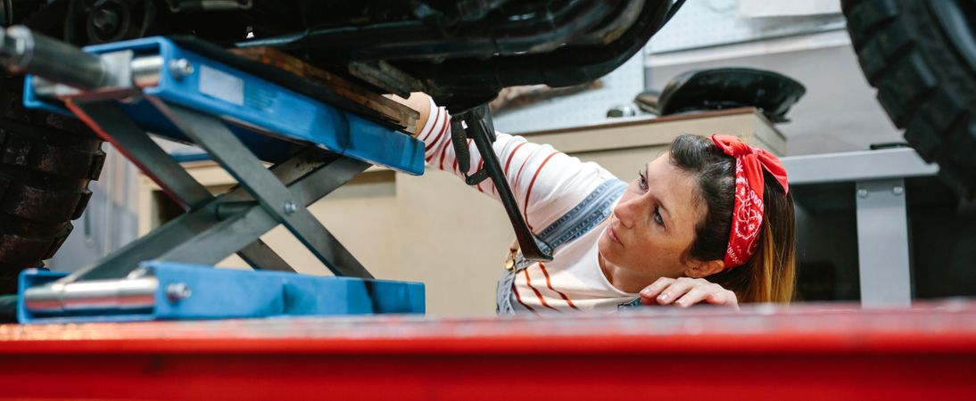 Mechanic woman checking motorcycle over platform