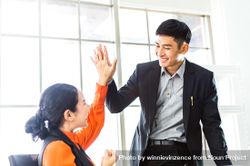 Happy successful Asian business man and woman giving high five for project success 5rljdb
