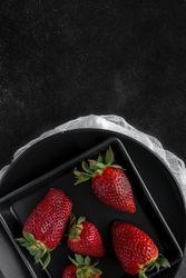 Red and fresh strawberries flat lay in dark dish