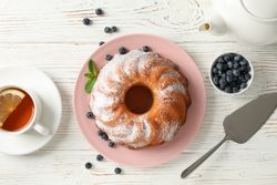 Cake with powder sugar and blueberry on wooden background, top view
