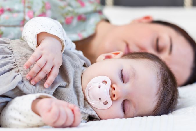 Young mother and her baby girl sleeping in the bed