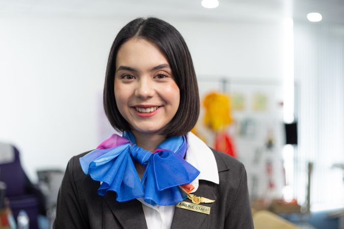 Smiling female in silk scarf flight attendant uniform standing in airport