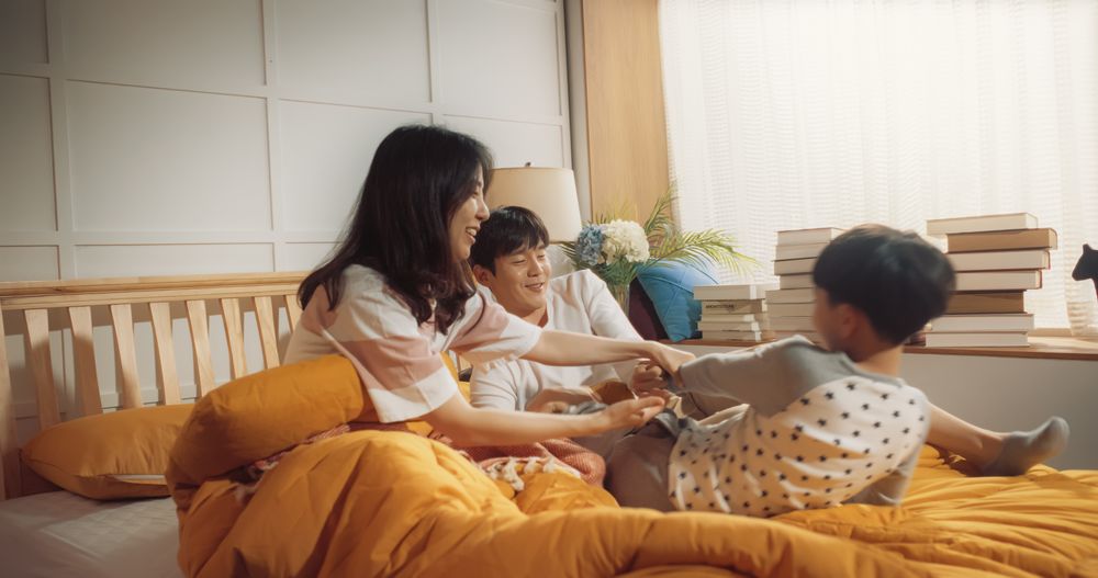 Cute Korean Family in the Morning: Active and Playful Child Running to his Parents' Bedroom to Wake Them Up.