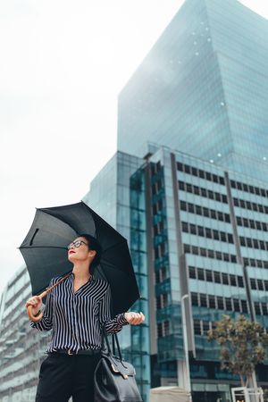 Businesswoman on city street with umbrella