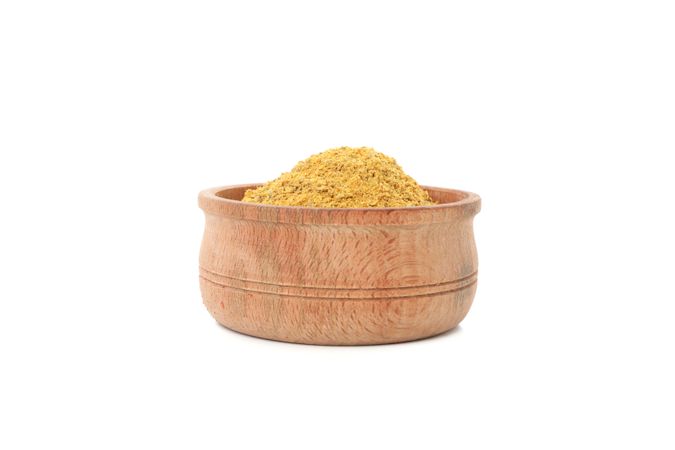 Side view of wooden bowl full of curry powder