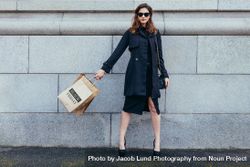 Stylish woman against wall with shopping bags 5r9vL3