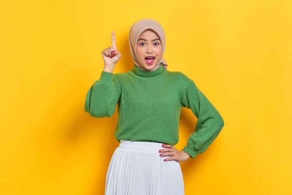 Surprised woman in headscarf holding up finger