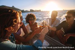 Cheerful young people on yacht drinking wine and beer with sun setting in bakground bGzPv4