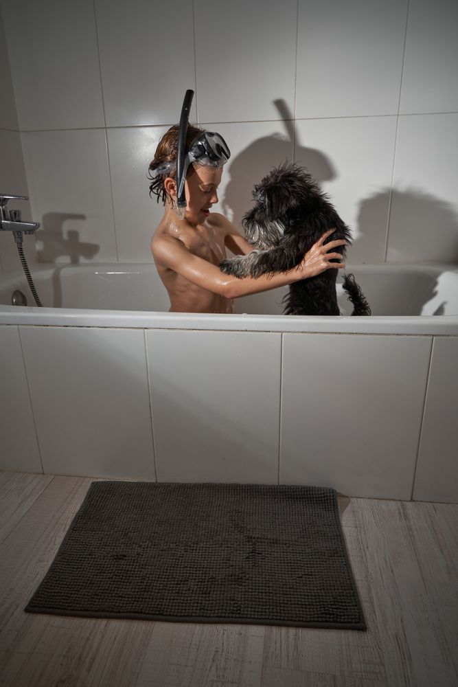 Boy playing with dog in bathtub