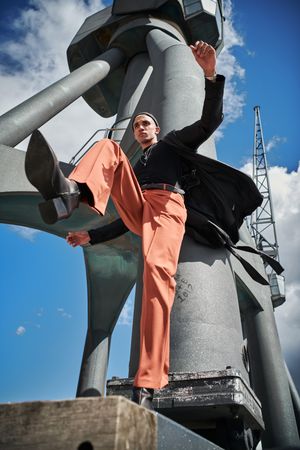 Up shot of fashionable young man taking step in industrial structure