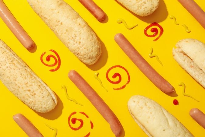 Flat lay with ingredients for hot dog on yellow background