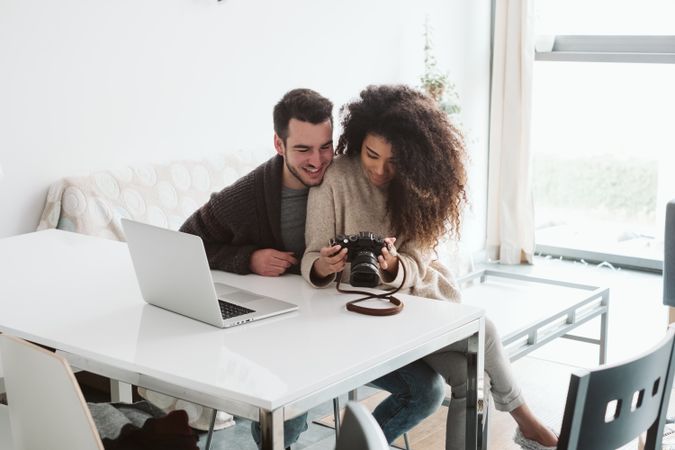 Multiracial couple looking at photo camera at home