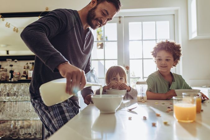 Man pouring milk into bowls for breakfast at home