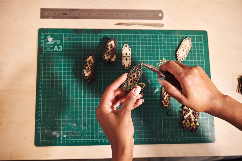 Manicured hands working with jewelry above a cutting board