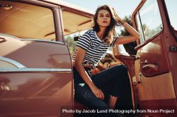 Beautiful young woman sitting in a vintage car 48Oj75