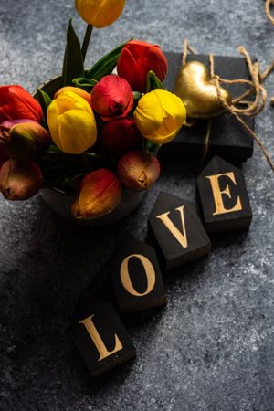 Valentine's day card concept with the word "love" and vase of tulips on grey counter