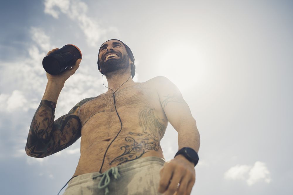 Shirtless man drinking during training