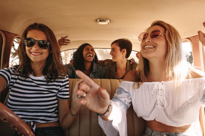 Young females on a road trip traveling by a car and laughing